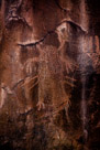 This little fellow is on a cliff face to the left of the main Dinwoody figures. He features a fully pecked torso, stubby arms with three fingered 'hands' on each and toes at each bottom corner. There are three to the left and possibly four to the right. The remains of a previous chalking are present. The figure has buffalo like 'horns' and of interest are the two strokes to each side of the torso.
