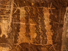 This is one of the geometric or outline figures that appears with Dinwoody style rock art and clearly in integral part of the tradition.  This one has four 'fingers' at each top corner and three 'toes' at each bottom corner.  There is a bold dot centered above the figure and two smaller dots centered above each vertical half. The bottom and top lines appear intended to be straight while the left side and possibly right were intended to be saw toothed. The interior of this figure is divided into six sections by various vertical modalities. The left vertical column is fully pecked and defined by sawtooth boundaries on both sides. The second column is less definite with the bottom section fully pecked and the balance shaded. The right boundary appears to be intended to be straight defining the left side of the third column. This column is mostly fully pecked with  a definite sawtooth right boundary in this fully pecked section. Above this both the left and right boundaries give indications of an intention to complete them with the sawtooth motif with the area shaded with sparse area pecking. The fourth column also features sparse pecking and has an interesting right boundary. This boundary is created by a single vertical line with a wavy line wrapping it from top to bottom. It also appears the previous two vertical lines may have started out in this way. Note that these wavy lines would not be suitable for making the sawtooth edge such as that on the right side of this column.  (Well it might be  suitable but does not appear to have been used). The right of this column is edged by a sawtooth defining the left edge of the sixth column. This column is fully pecked and while the right edge is mostly straight there is pecking consistent with sawteeth of the right side as well. The toes at the lower right have some shading pecking and there is a dot under the second column. They appear to date from the original. Significant???