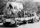 Aged 9 years, 5 months, 24 days.
November 12, 1951.
We actually won first prize in the parade. I am the kid on the front fender with the feathers on his head. 
From the back - Setting on truck bed is George Bean, Standing with gun is Brian Davis, in back of wagon is unknown boy, Donald Kothmann and Ramior Sanchez, on side of truck looking is Duck Menzies. Note that the chickens in the coop are real and the guns - those babies are every one real guns. Probably not loaded.