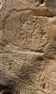 This shield is dominated by a 'masked' figure that is flsnked by zoomorphs, possible representing lions. The multiple lines below may be tool sharpening artifacts in addition to some arrows(spears?).