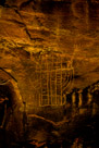 Now back to this glyph.  First note that the head dress appears to be a single tall spike above the head with regular side spikes on the sides. Note the wavy lines under the right hand. There are four fingers on the visible hand but only three minimalist toes on each 'foot' The head appears to have originally had much detail which is lost to mineralization. Note the rounded sides with interior lines in each.  The main body is divided by three strong vertical bars which are divided by very irregular horizontal lines.