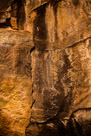The head of this glyph has been lost to mineralization or spalling. It is a 'winged' figure with strong interior lining. Two bold vertical bars divide the body into three vertical columns.  Of particular note is the wavy lines descending from both 'wings'.  They are dim but most definitely there. The horizontal lines in the body, particuliarly the center column, have an offset to them like an  attempt to match up or connect the right horizontal lines with the left horizontal lines in a one-for-one fashion. Feet are indicated on stubby legs. The right foot has four toes while the right foot has at least three toes but may be interpreted to have four. The symetry of the 'wings' can not be determined.