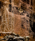Now the next figure. Again the chalk is not helping us here.   
First note the little flying figure to the upper left of the main figure's head.    
To the lower left, is that an owl like figure??? And to the right are clearly two owl like fitures.  
And the main figure is clearly owl like with two very prominent 'horns' and large 'eyes' . The arms are bold with elbows indicated and four fingers on each hand. The arms and 'chest' are fully pecked. powerful wavy lines descend from the left and right arms. The bottom of the torso is fringed possibly three 'toes' indicated to the left. The main torso is divided into two equal sections by a bold vertical line. The interior of the torso is filled with upward angled horizontal lines  and crossed by rows of dots. Vertical wavy lines descend from the chest area indifferently down through the lower torso.  A row of bold dots  appears to define the right side of this figure. .