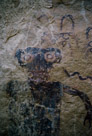 Another closeup of the head of the left figure. The circles above the head are clear and also it is clear that spalling has damaged and possibly removed other circles with streamers. It is hard to tell if this figure ever had any interior detail other than the obvious striping used to create the torso. The paint obviously had varing density. Significant?? The neck appears to have horizontal painting or brush marks in a lighter color.  Is this a 'mouth', necklace, collar?? And the eye 'pupil's appear to be different color.